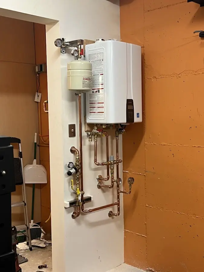 Plumbing technician inspecting water heater connections in Ripley
